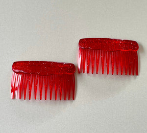 A photo of 5 pairs of short hair combs, in bright coloured plastic; embedded with glitter. Clockwise from top are yellow, neon pink, red, green and blue.