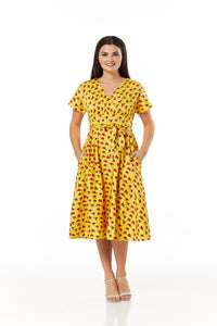 Voluptuous VIntage Darcey Brights Floral Dress by Timeless, a yellow short sleeved retro silhouette dress with red floral pattern and crossover neckline. the model is showing off the pockets.