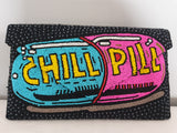 Voluptuous Vintage Hand Beaded Luxury Clutch Bag - Chill Pill Bag by Rikki . A huge blue and pink pill with yellow "chill pill" written on it, adorning the whole front of a heavily beaded black bag