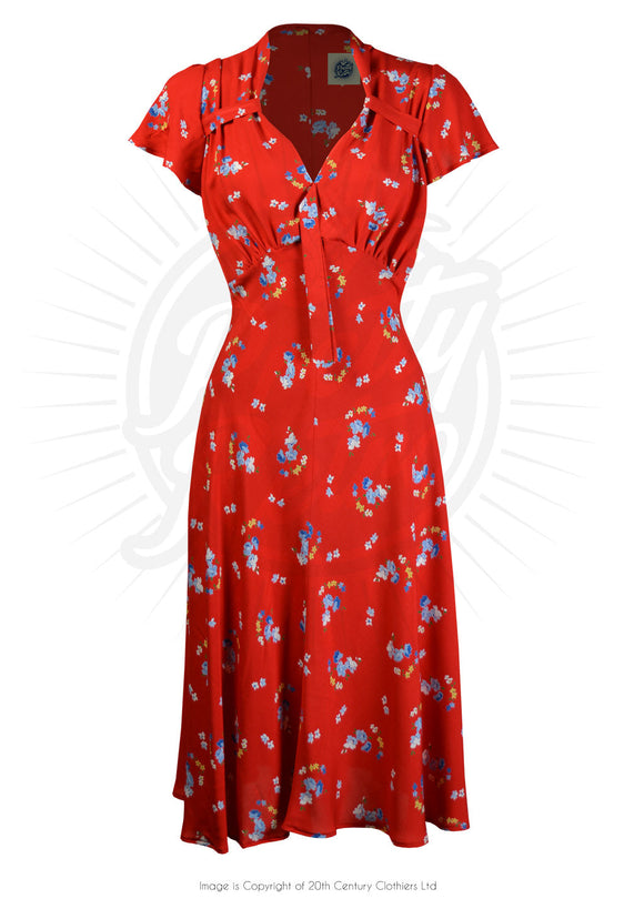 Voluptuous Vintage Violet Floral 40s Tea Dress by Pretty Retro . a bold red 40s style dress with sweetheart neckline and gathers at the bust and shoulder. There is a small tie at the base of the sweetheart neckline and the front panel of the dress is smooth. A delicate blue floral pattern adorns the dress.